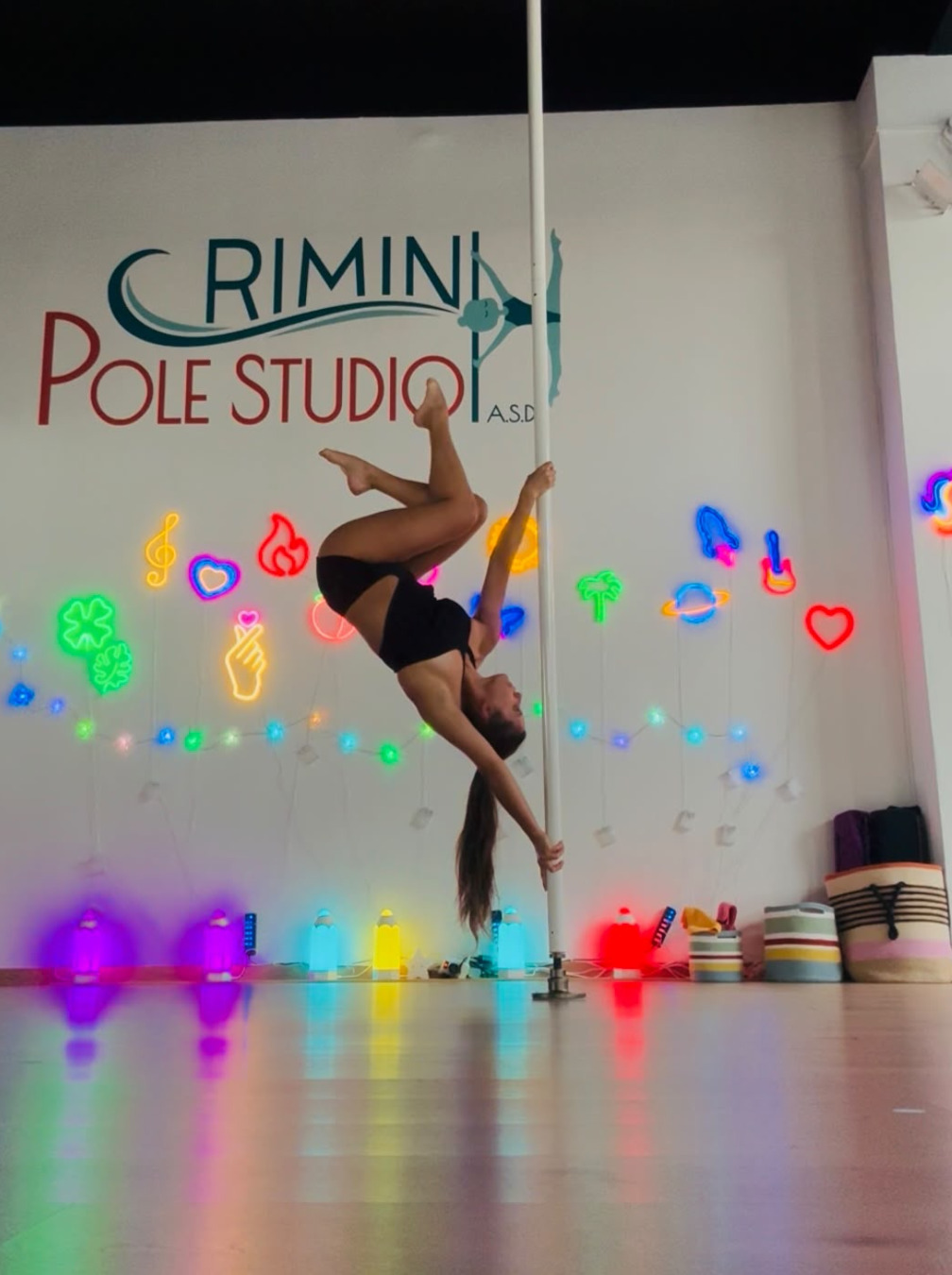 chiara lamponi istruttrice di pole dance della a.s.d. rimini pole studio esegue una inversione al palo